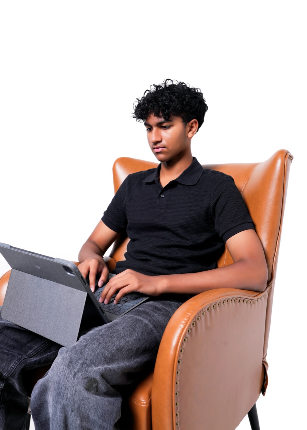 Ritham typing on a laptop in a leather armchair